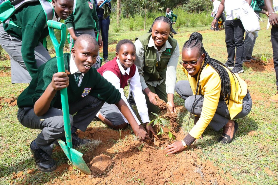 Environment CS Deborah Mulongo plants a tree with a group of students.